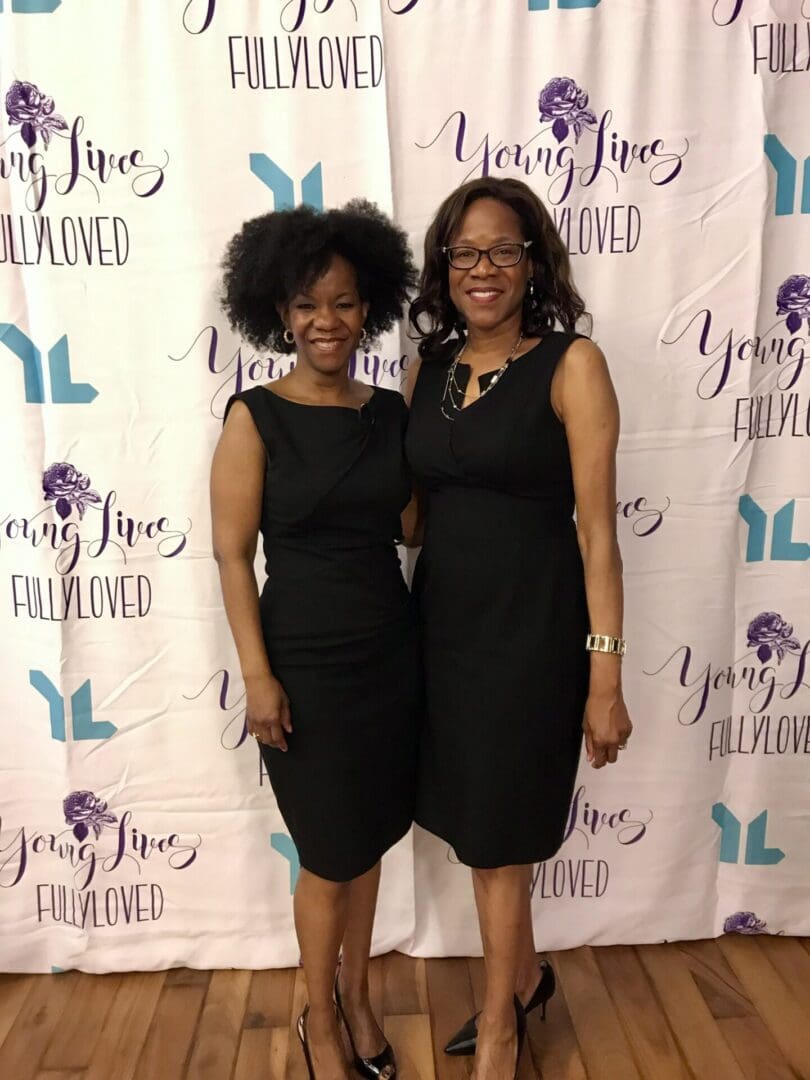 Two women in black dresses posing for a picture.